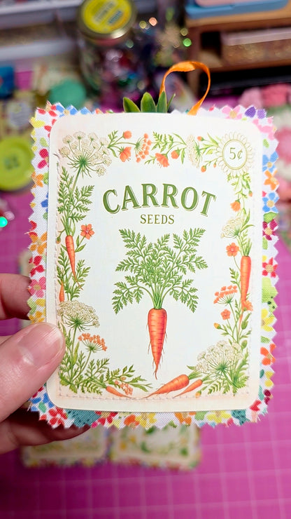 Card with carrot seeds illustration and decorative border held by a hand.