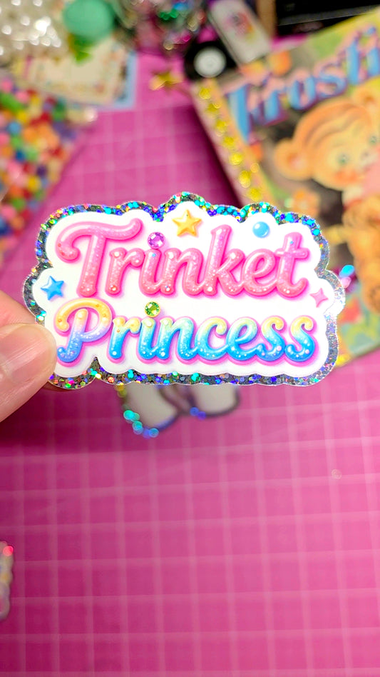 Colorful 'Trinket Princess' sticker held over a pink checkered background