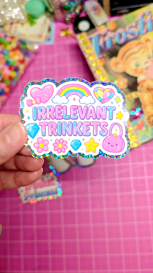 Colorful sticker with 'Irrelevant Trinkets' text held over a pink grid background