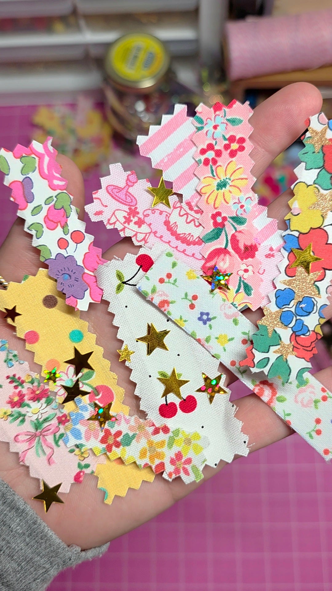 Hand holding colorful decorative paper cutouts with floral and star patterns.