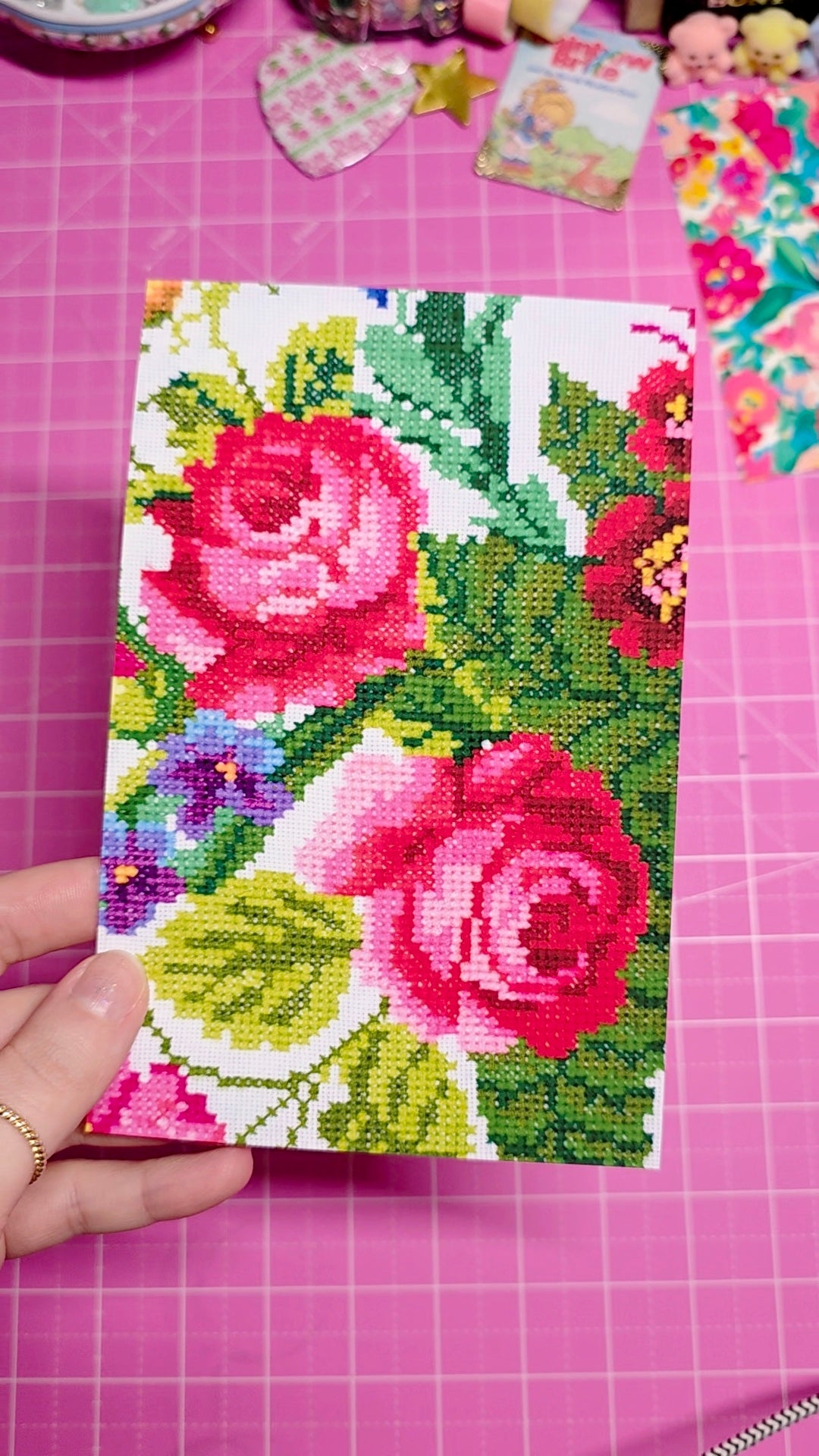 Floral cross-stitch design on a pink cutting mat