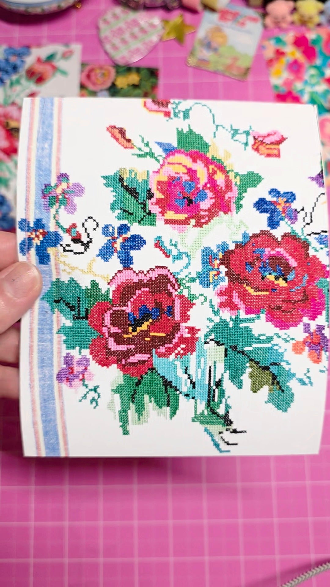 Cross-stitched floral design on a piece of fabric with a pink background