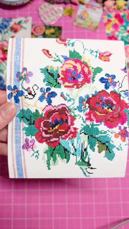 Cross-stitched floral design on a piece of fabric with a pink background