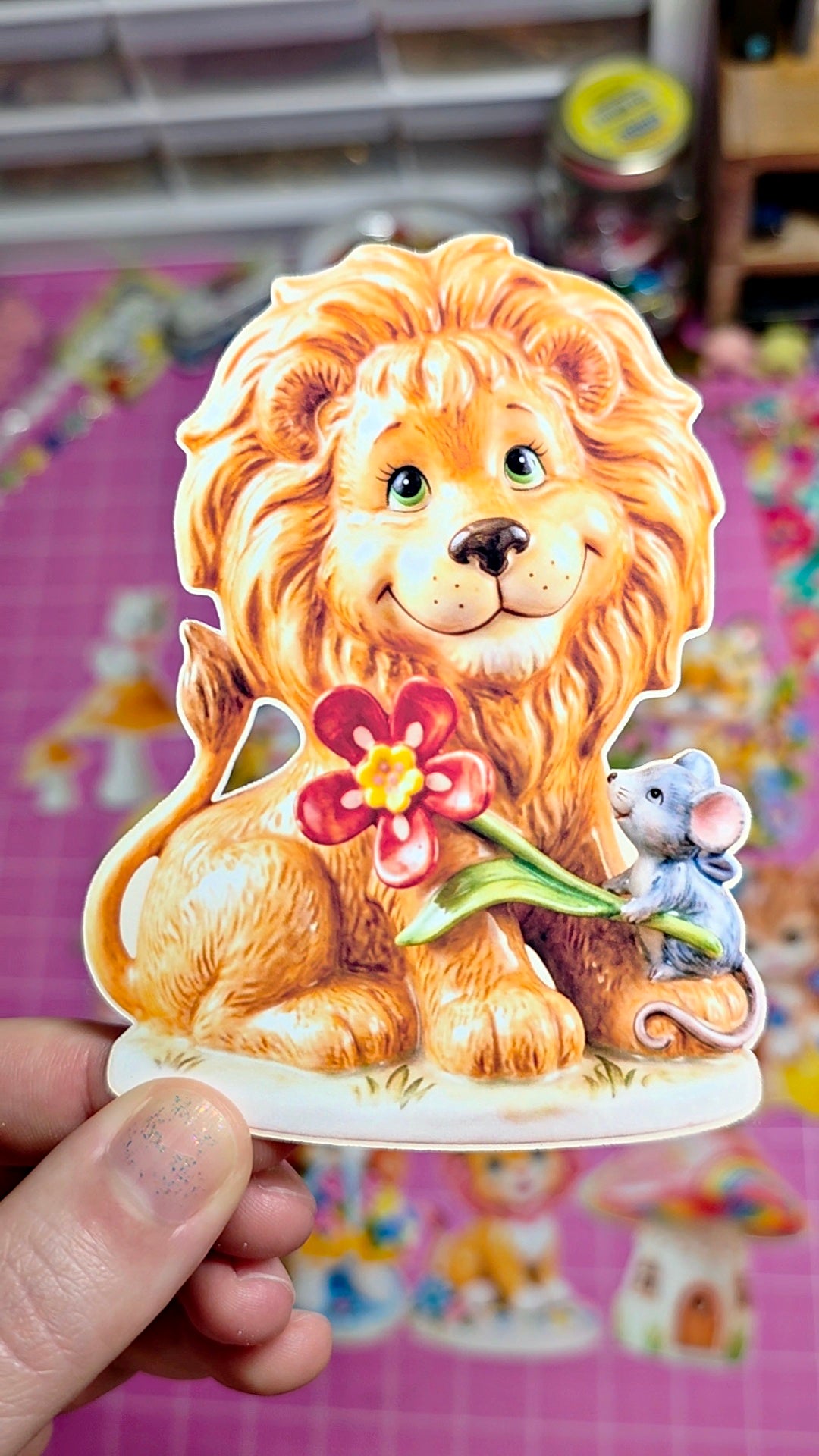 Decorative lion figurine with a flower and mouse on a pink background