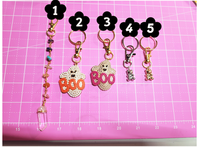 Five decorative keychains with numbers on a pink cutting mat