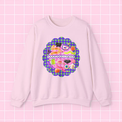 A light pink crewneck sweatshirt featuring a colorful retro graphic with the text 'HAPPY BIRTHDAY' on a purple and green plaid scalloped background, displayed against a pink grid backdrop.