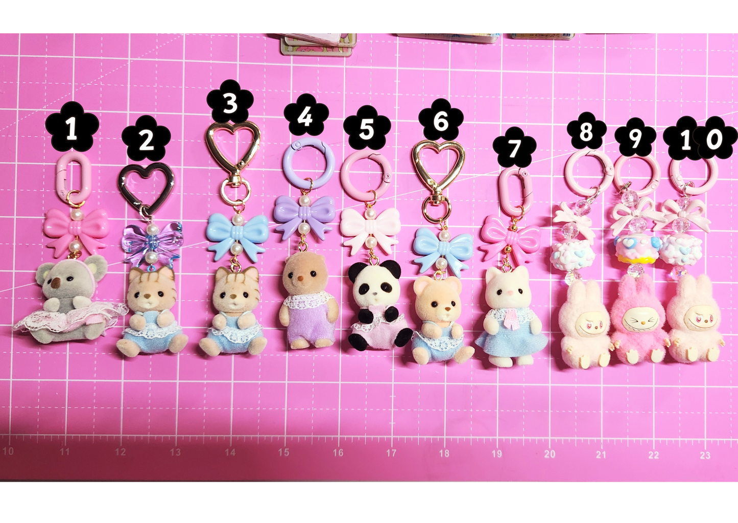Row of small animal keychains with numbers on a pink grid background