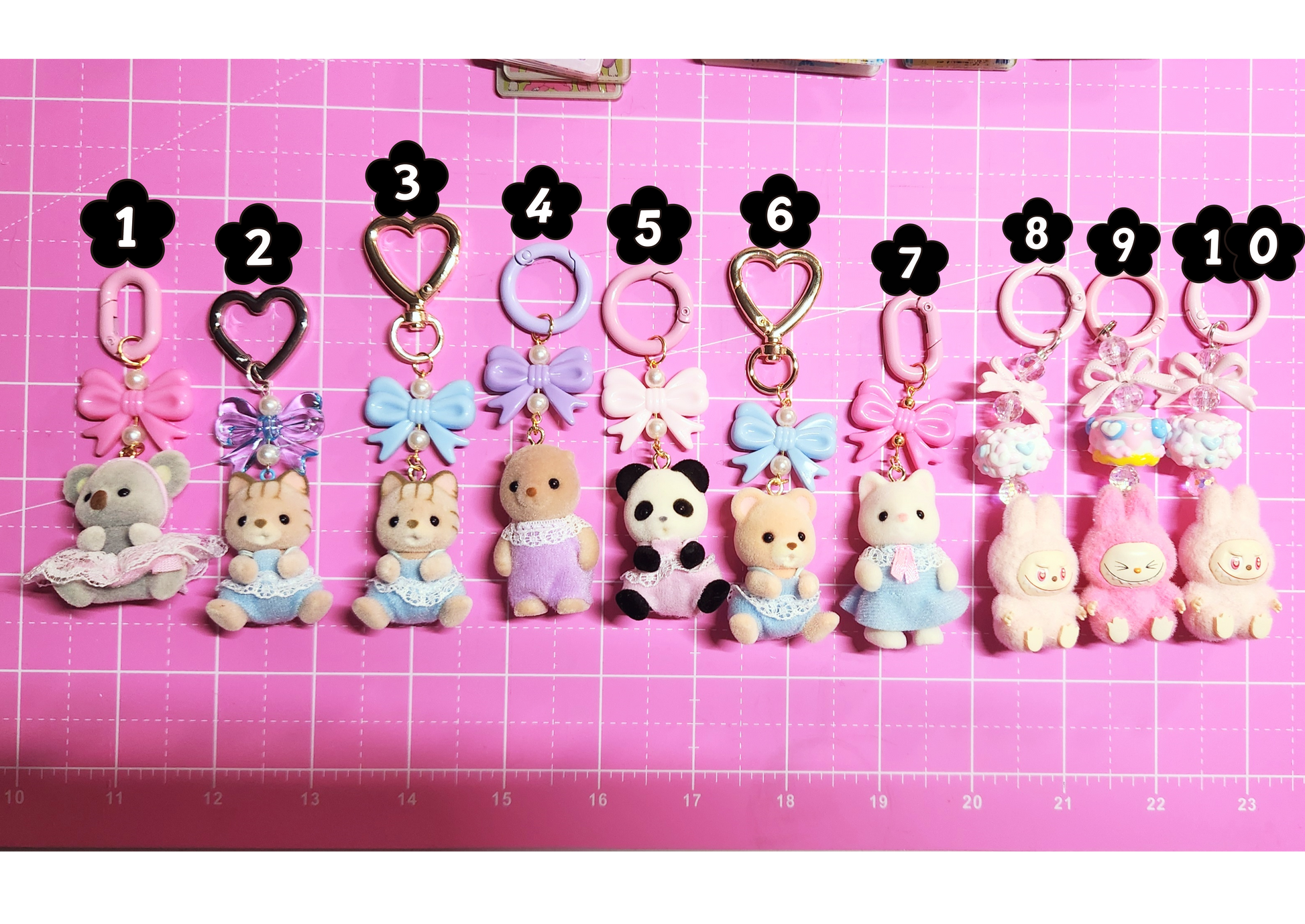 Row of small animal keychains with numbers on a pink grid background