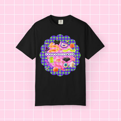 A black short-sleeve t-shirt with a colorful 'Happy Halloween' graphic on the chest, displayed against a pink grid background.
