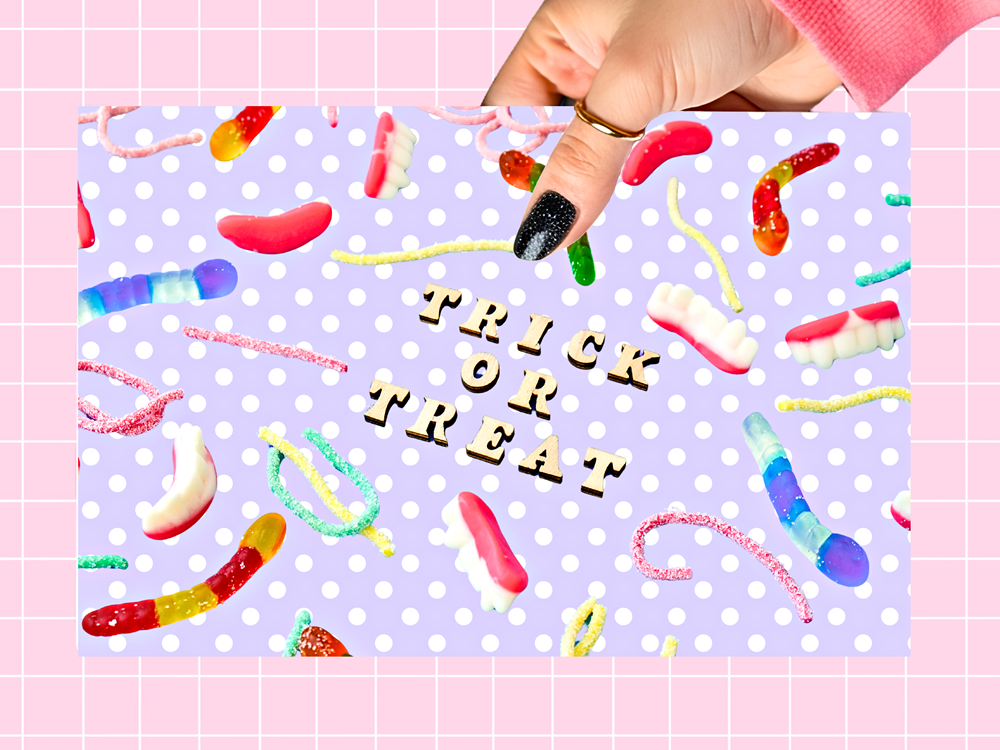 A hand with glittery black nail polish holds a square card that reads 'TRICK OR TREAT' in gold letters, surrounded by colorful candy illustrations on a lavender polka-dot background. The card is set against a pink grid backdrop.