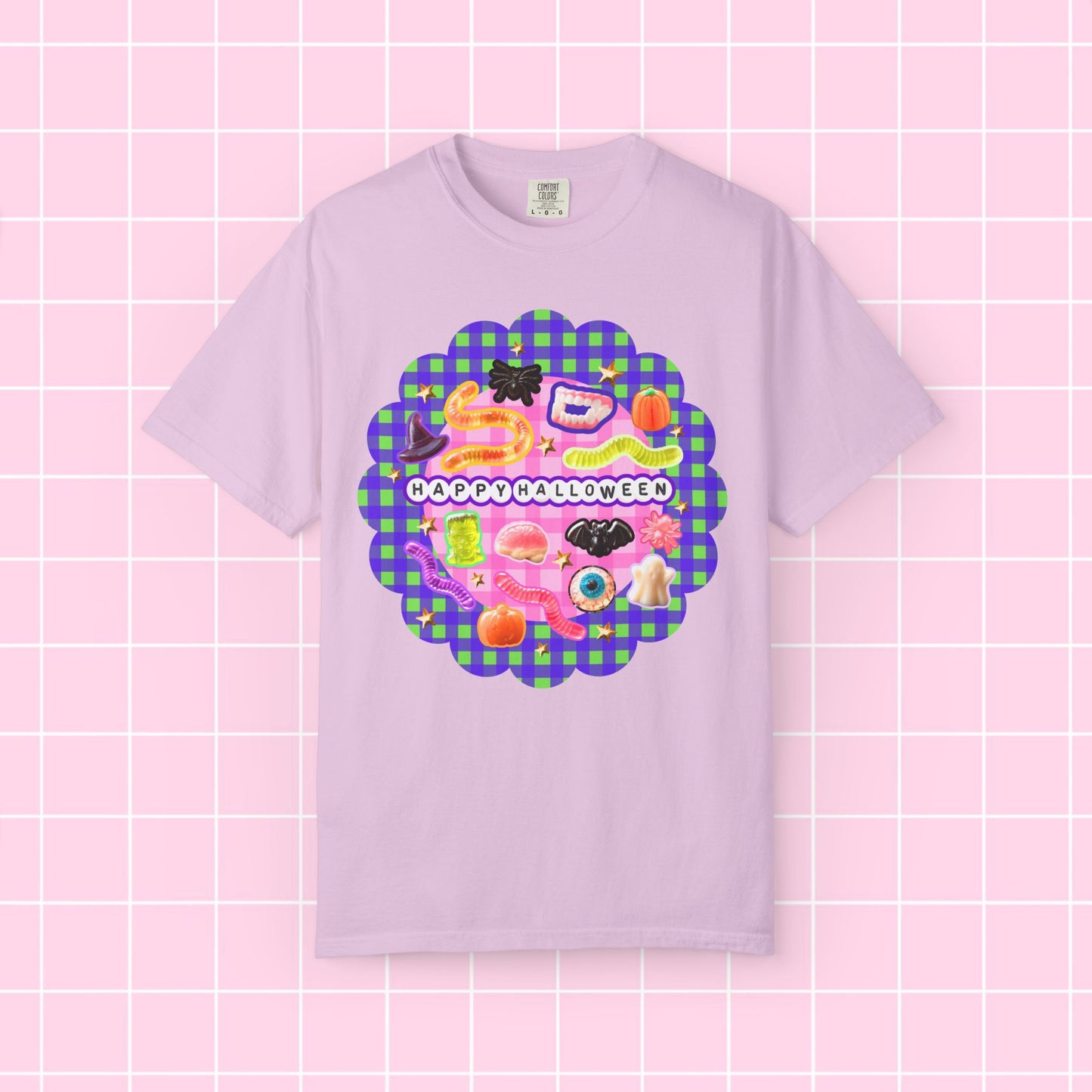 A light purple short-sleeve t-shirt with a colorful 'Happy Halloween' graphic on the chest, displayed against a pink grid background.