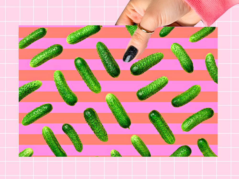 A rectangular print or card featuring a repeating pattern of green cucumbers on pink and coral horizontal stripes, held by a hand against a pink grid background.