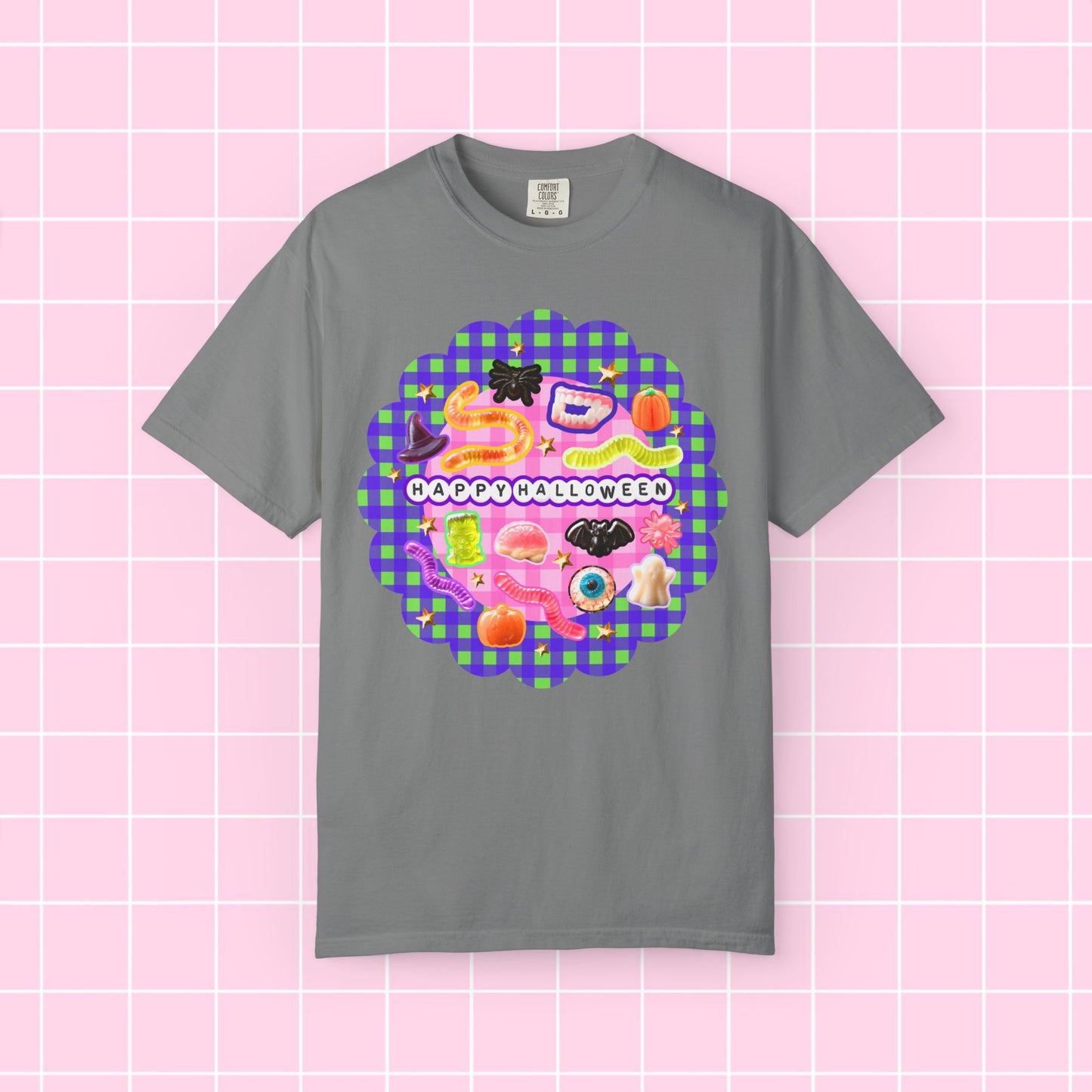 A gray short-sleeve crewneck t-shirt featuring a colorful 'Happy Halloween' graphic print on the front, displayed against a pink grid background.