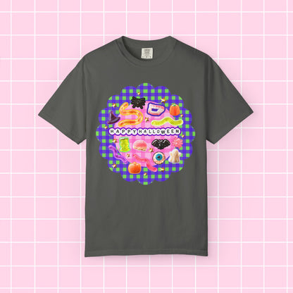 A gray short-sleeve crewneck t-shirt featuring a colorful 'Happy Halloween' graphic print on the front, displayed against a pink grid background.