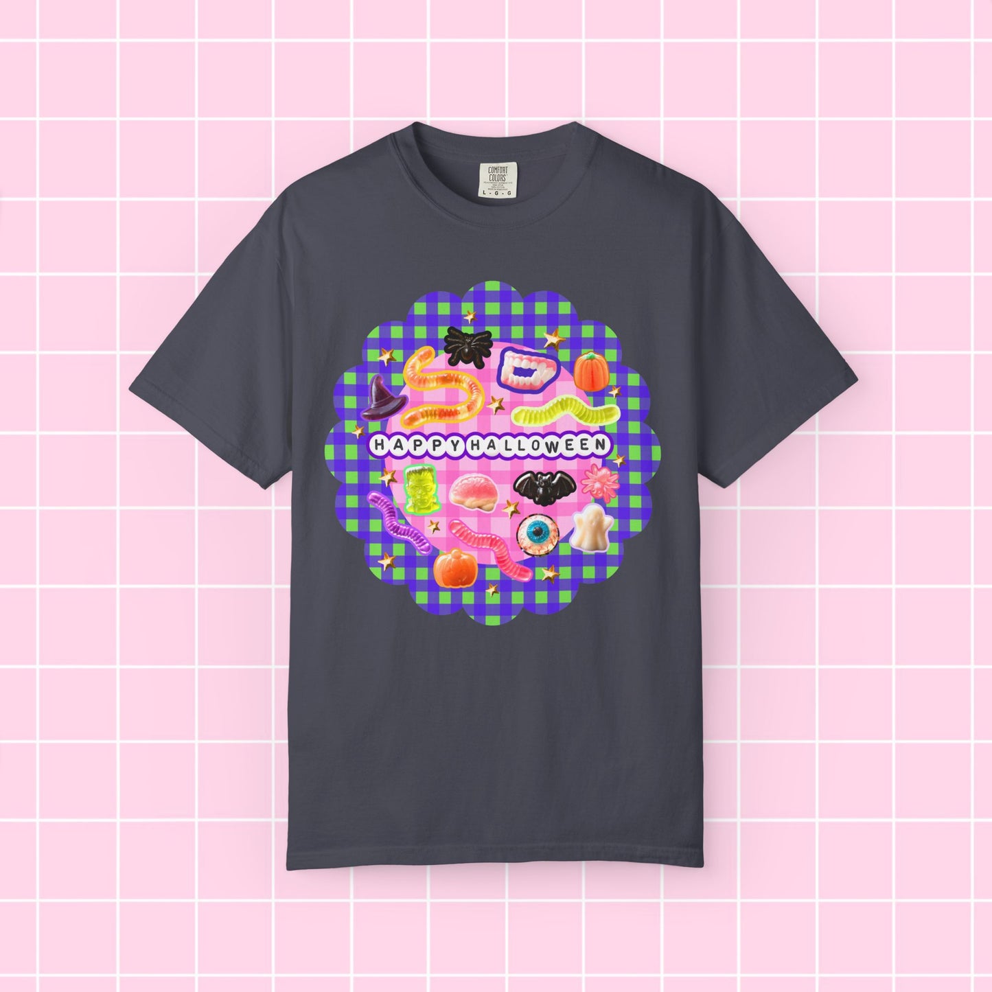 A dark charcoal gray t-shirt with a colorful 'Happy Halloween' graphic on the chest, displayed against a pink grid background.
