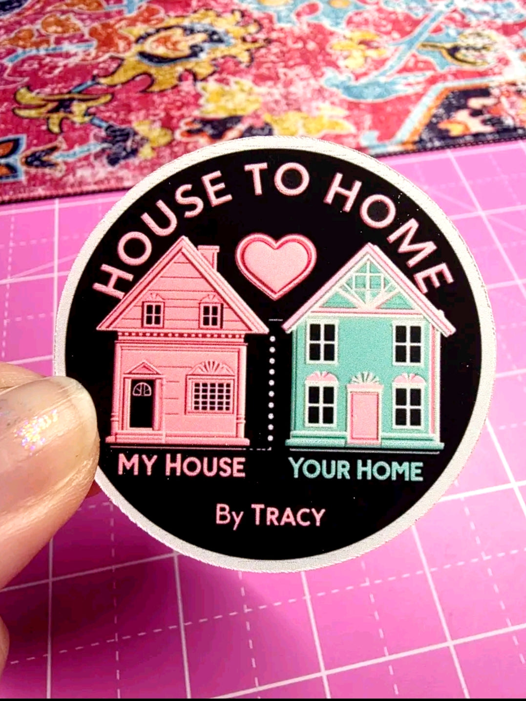 Sticker with houses and text 'House to Home, My House Your Home by Tracy' on a pink grid background.