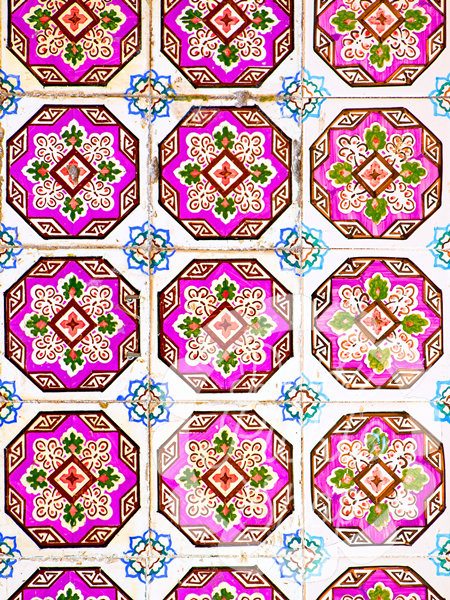 Pattern of decorative tiles with pink and green designs on a white background