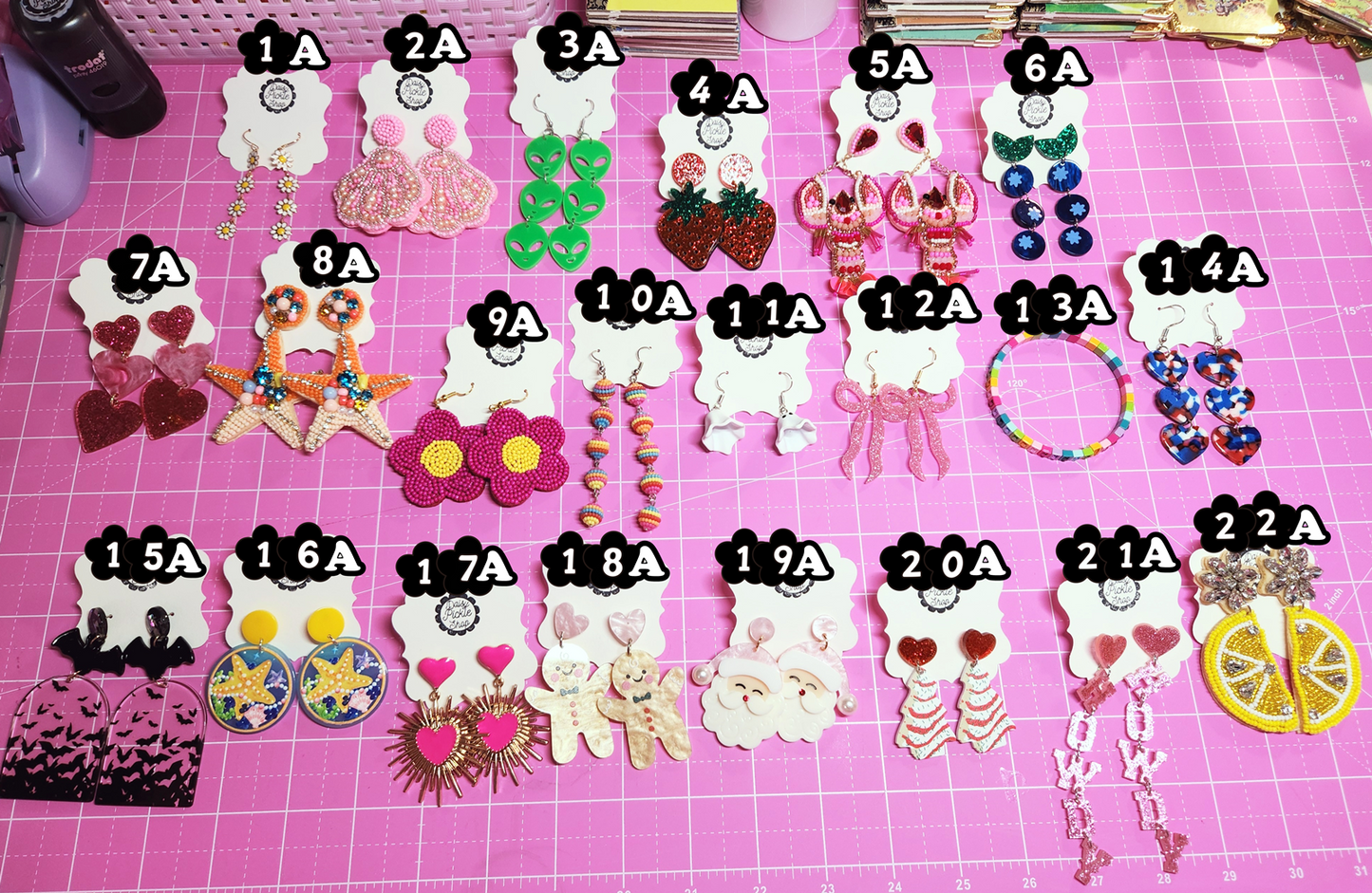 Assorted earrings on a pink surface with labels