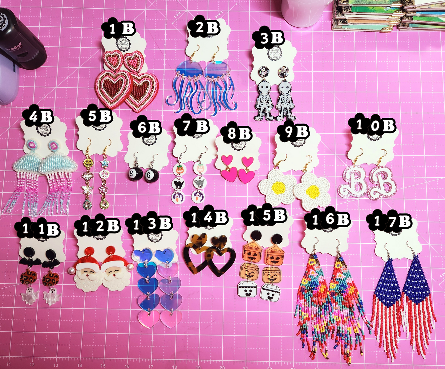 Assorted earrings on a pink surface with labels