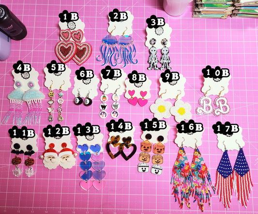 Assorted earrings on a pink surface with labels