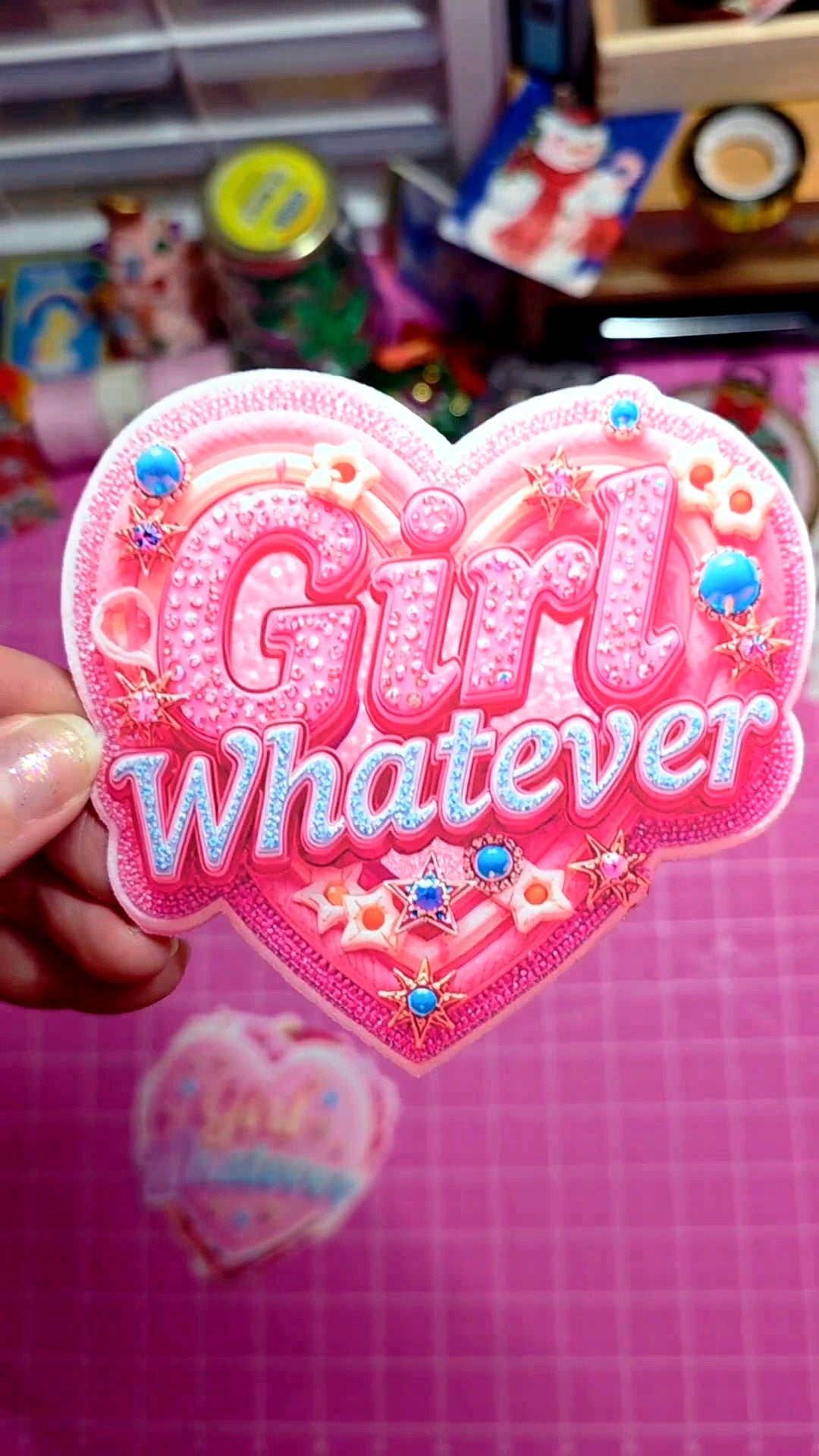 Heart-shaped pink patch with 'Girl Whatever' text on a grid background