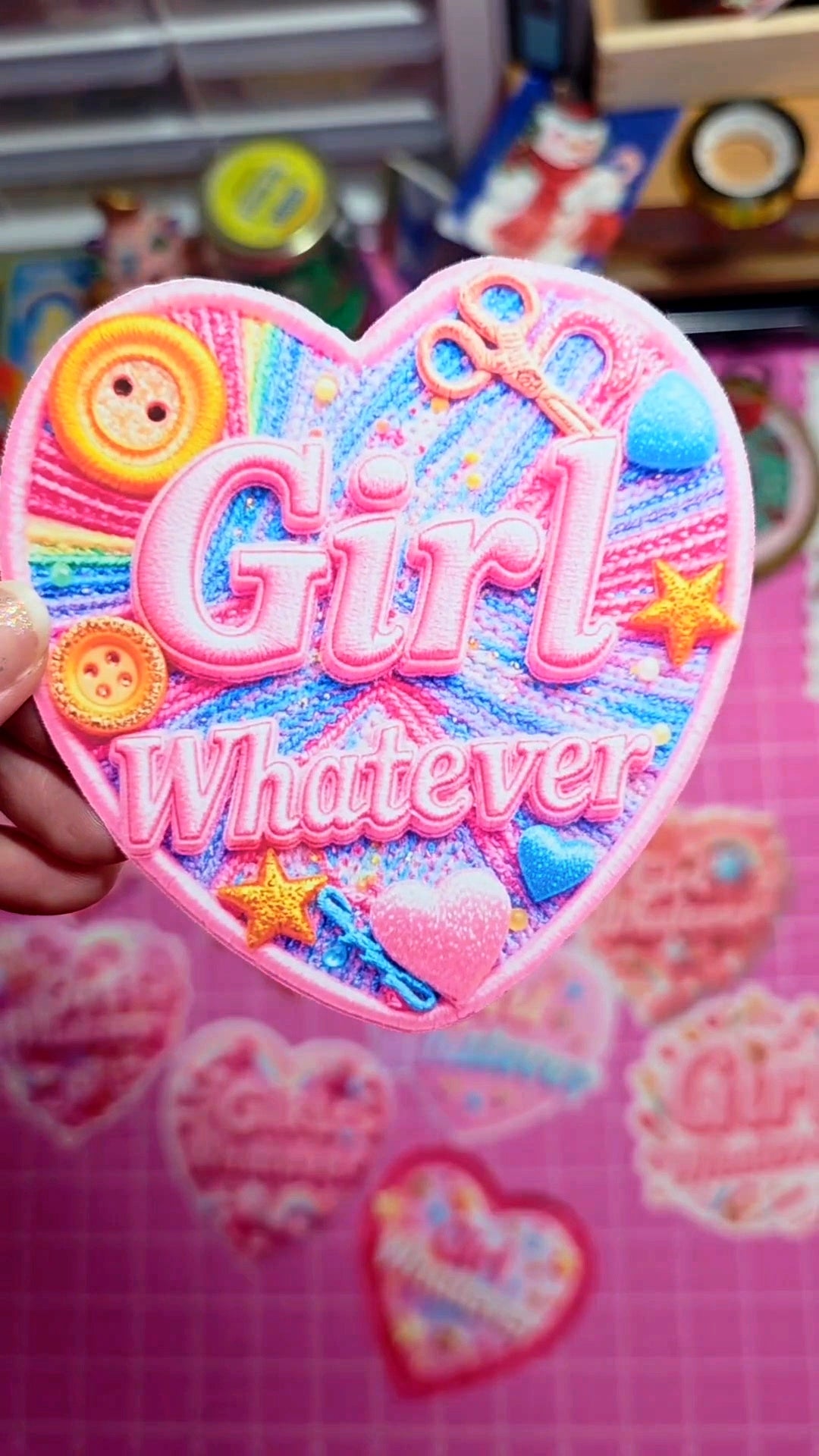 Colorful heart-shaped patch with 'Girl Whatever' text on a pink background