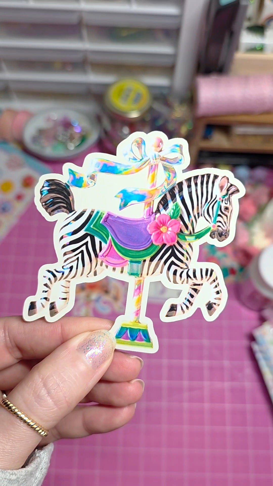 Colorful zebra and carousel sticker held by a hand with a blurred background