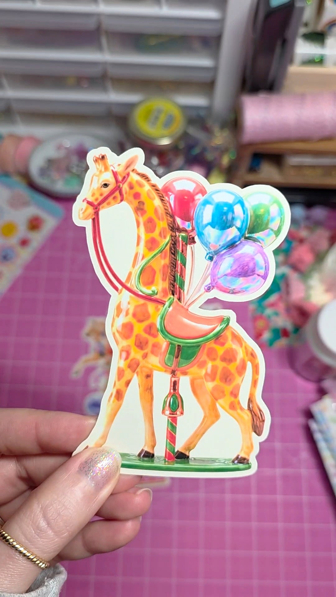 Colorful horse-shaped card with balloons held by a hand on a pink background