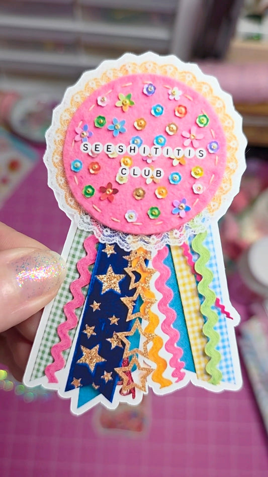Colorful ribbon badge with 'SEESHITITIS CLUB' text held by a hand.