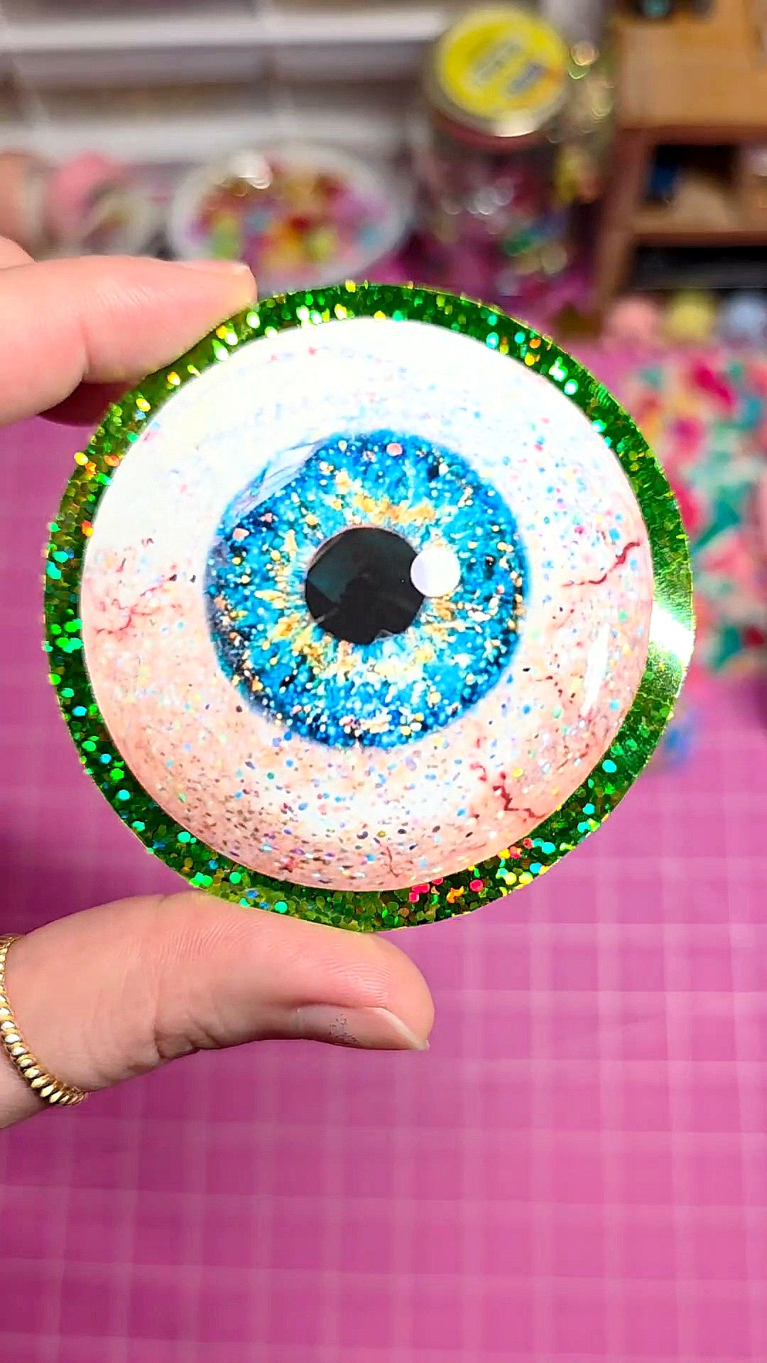 Colorful eye-shaped object held by a hand with a blurred background