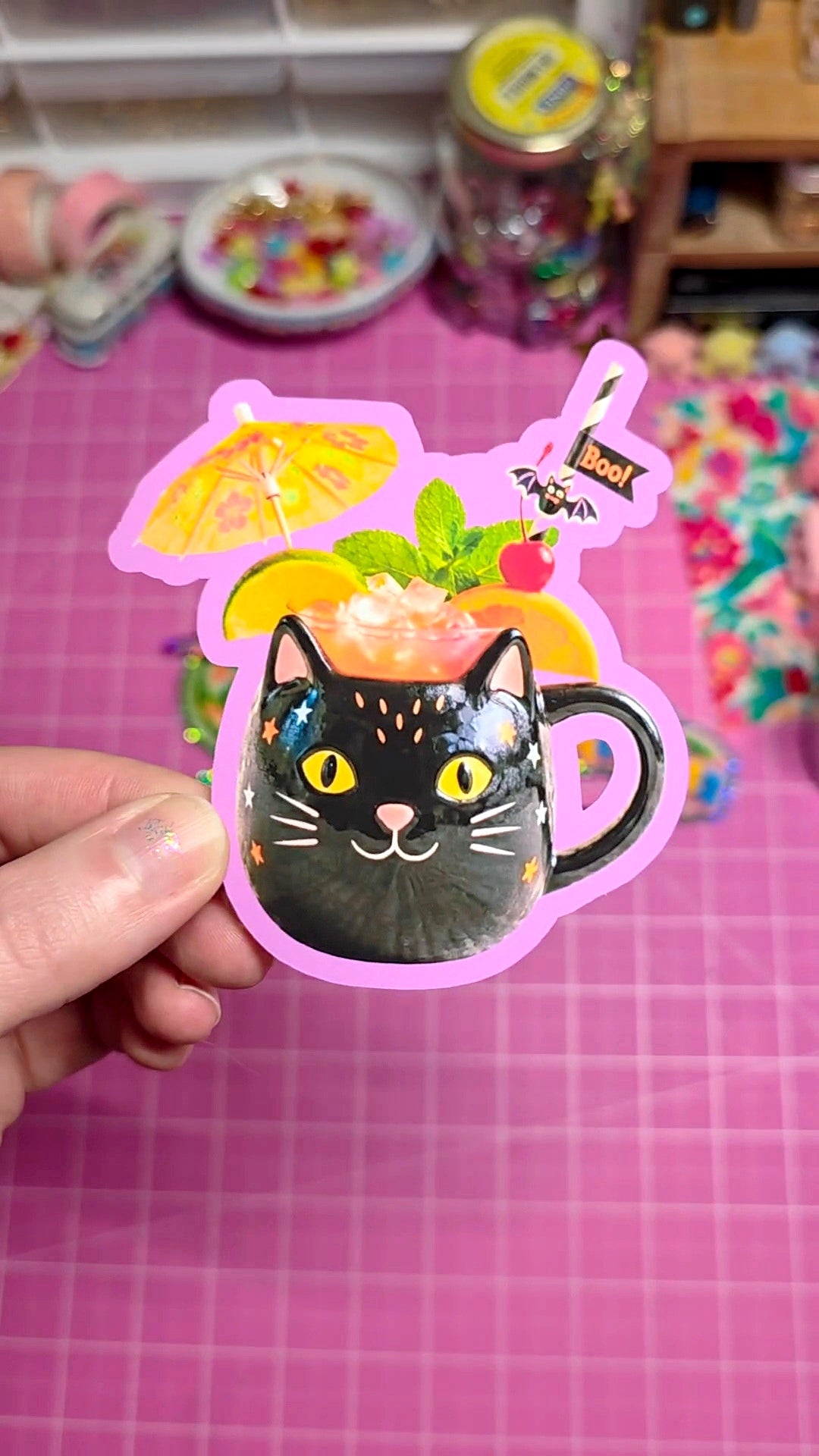 Sticker of a black cat with a colorful drink on a pink background