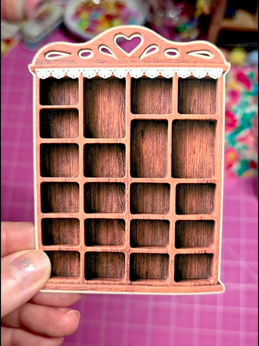 Wooden jewelry organizer with decorative pink frame held by a hand on a colorful background