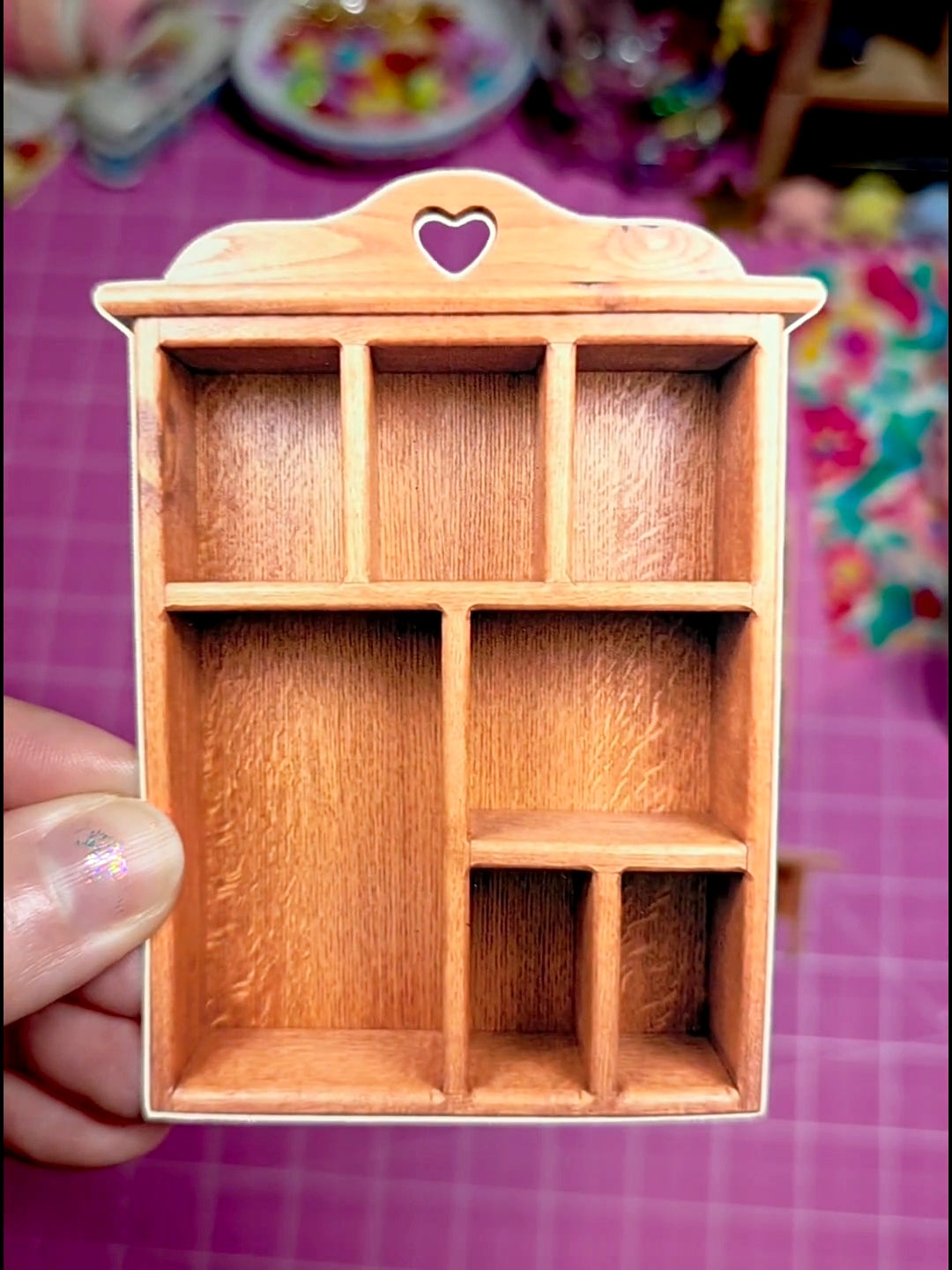 Wooden jewelry box with compartments on a pink checkered background