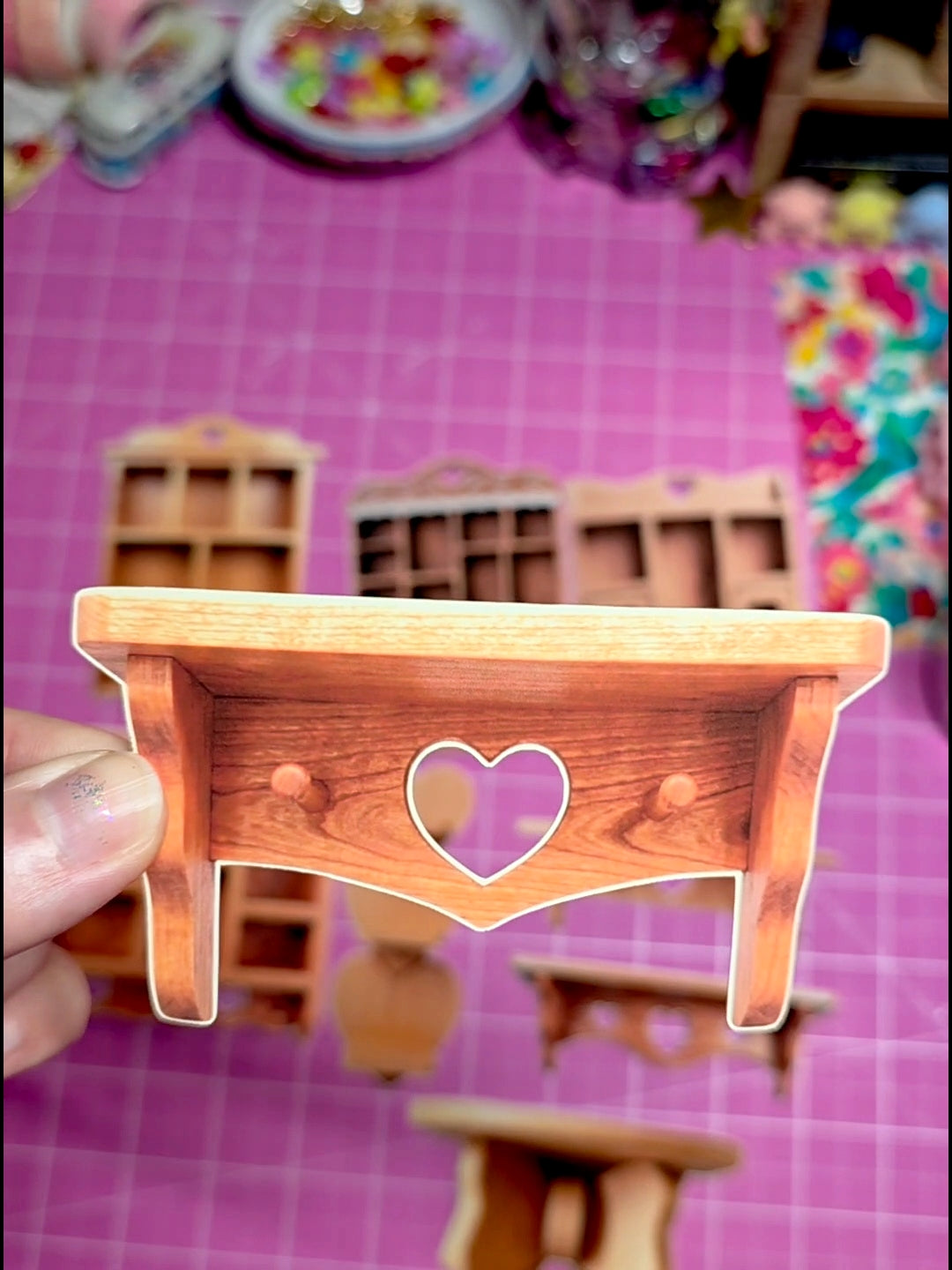 Small wooden desk with a heart cutout on a pink grid background