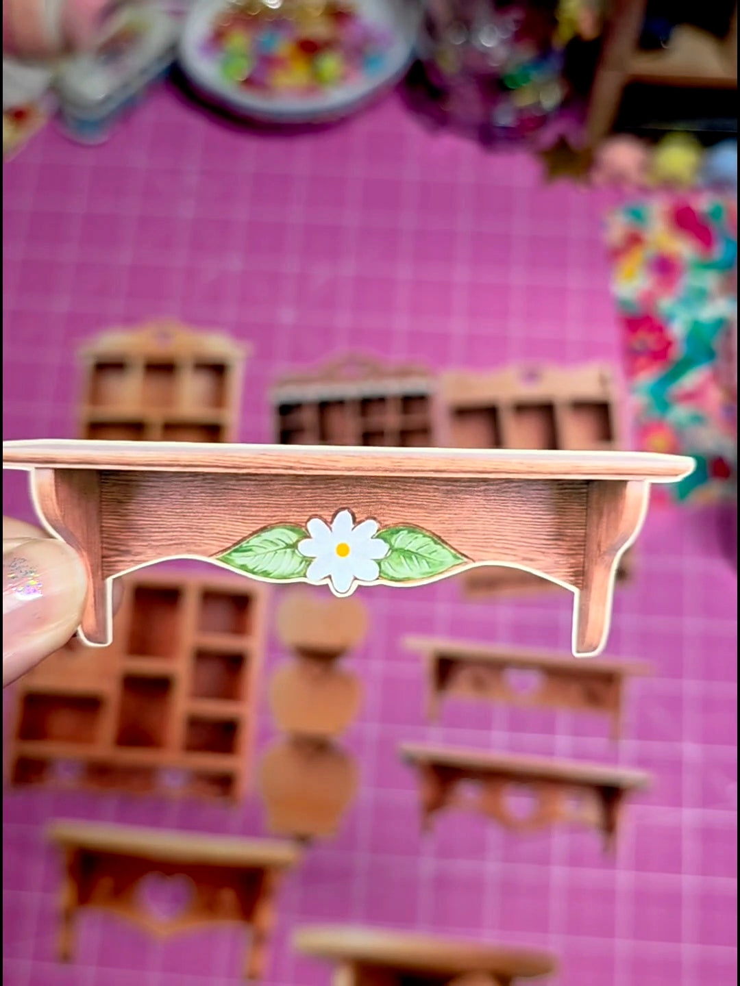 Small wooden shelf with a decorative flower design on a pink surface