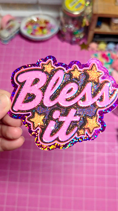 Holographic sticker with 'Bless it' text held over a pink grid background