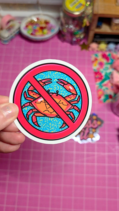 Sticker with a colorful design of a crab inside a prohibition symbol held over a pink grid background.