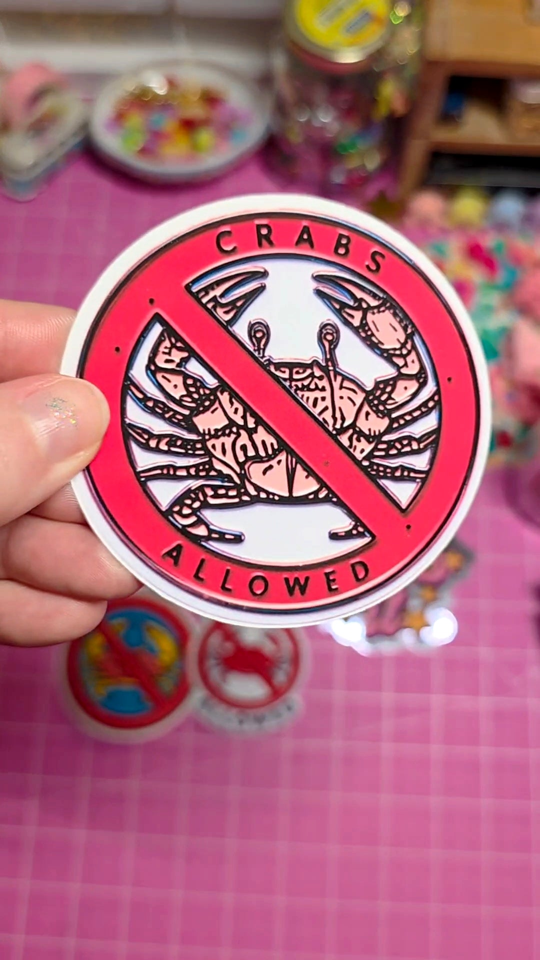 Sticker with 'CRABS ALLOWED' design held by a hand on a colorful background