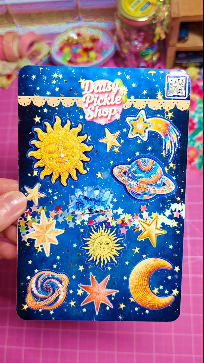 Sticker pack with celestial designs held by a hand on a colorful background