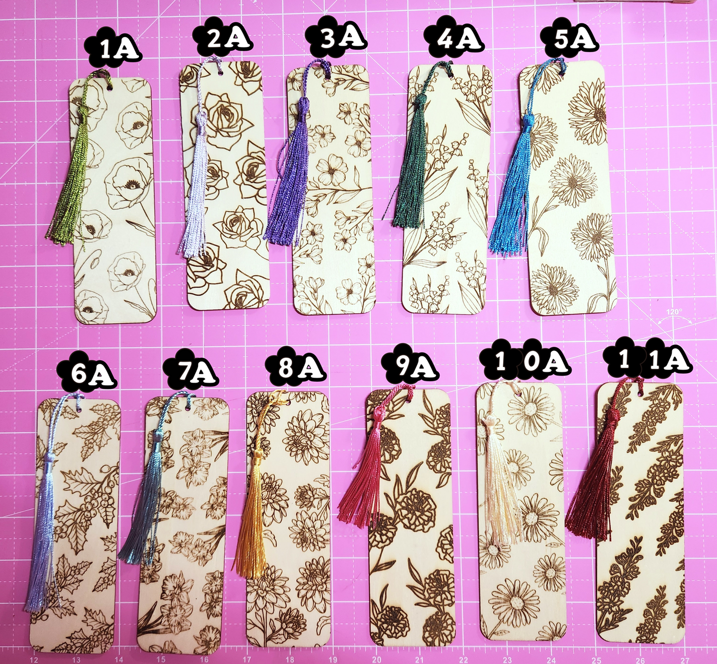Set of twelve decorative bookmarks with tassels on a pink cutting mat.
